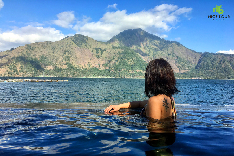Mandi air panas saat berwisata ke Danau Batur Bali di kaki Gunung Batur, danau alam indah di Pulau Bali