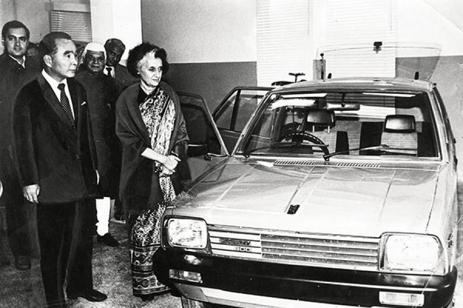 Perdana Menteri Indira Gandhi, dengan Rajiv Gandhi dan ND Tiwari di latar belakang, memeriksa sebuah model mobil sebelum meresmikan pabrik Maruti di Delhi pada tanggal 14 Desember 1983 