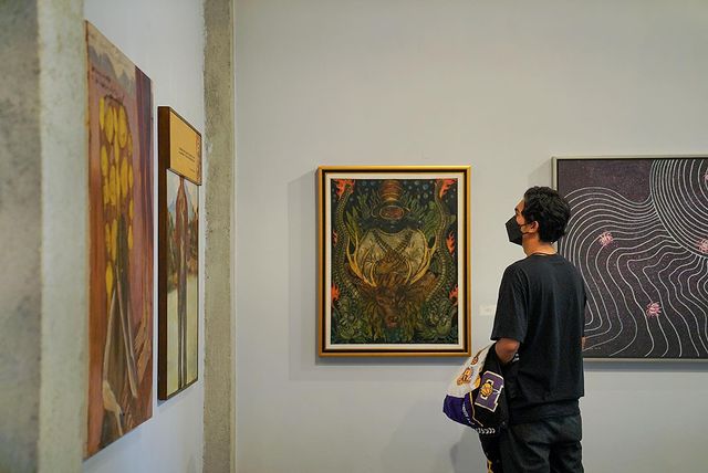 Seorang pengunjung tengah menikmati lukisan di Pameran Ludens. | Foto: @museumdantanahliat/Instagram