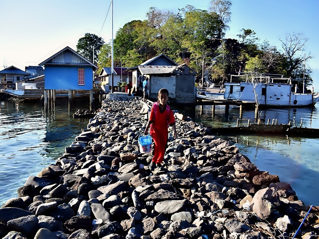 Seorang anak warga Pulau Koja Doi melintasi jembatan batu menuju sekolahnya | Foto: Ebed de Rosary/Mongabay Indonesia